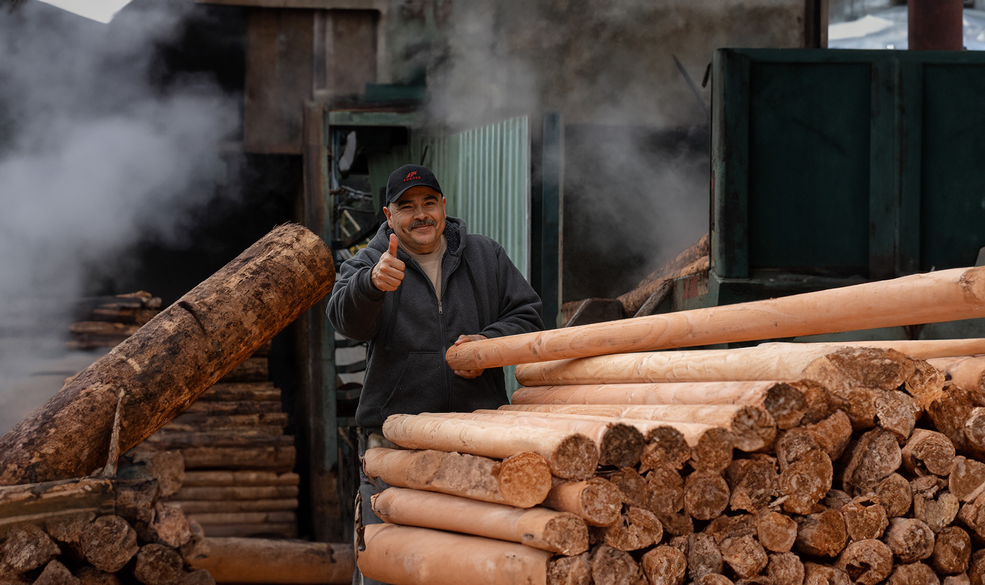 lumber mill worker thumbs up log cores by Marcus Kauffman